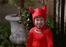 Small child dressed in a devil costume waving