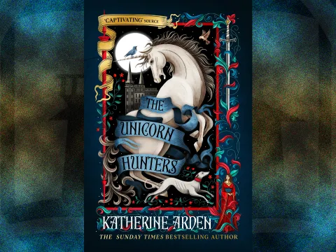 Featured image for The Unicorn Hunters by Katherine Arden. The intricate, medieval-tapestry-style illustration features a rearing white unicorn wrapped in a flowing blue banner that displays the book's title.